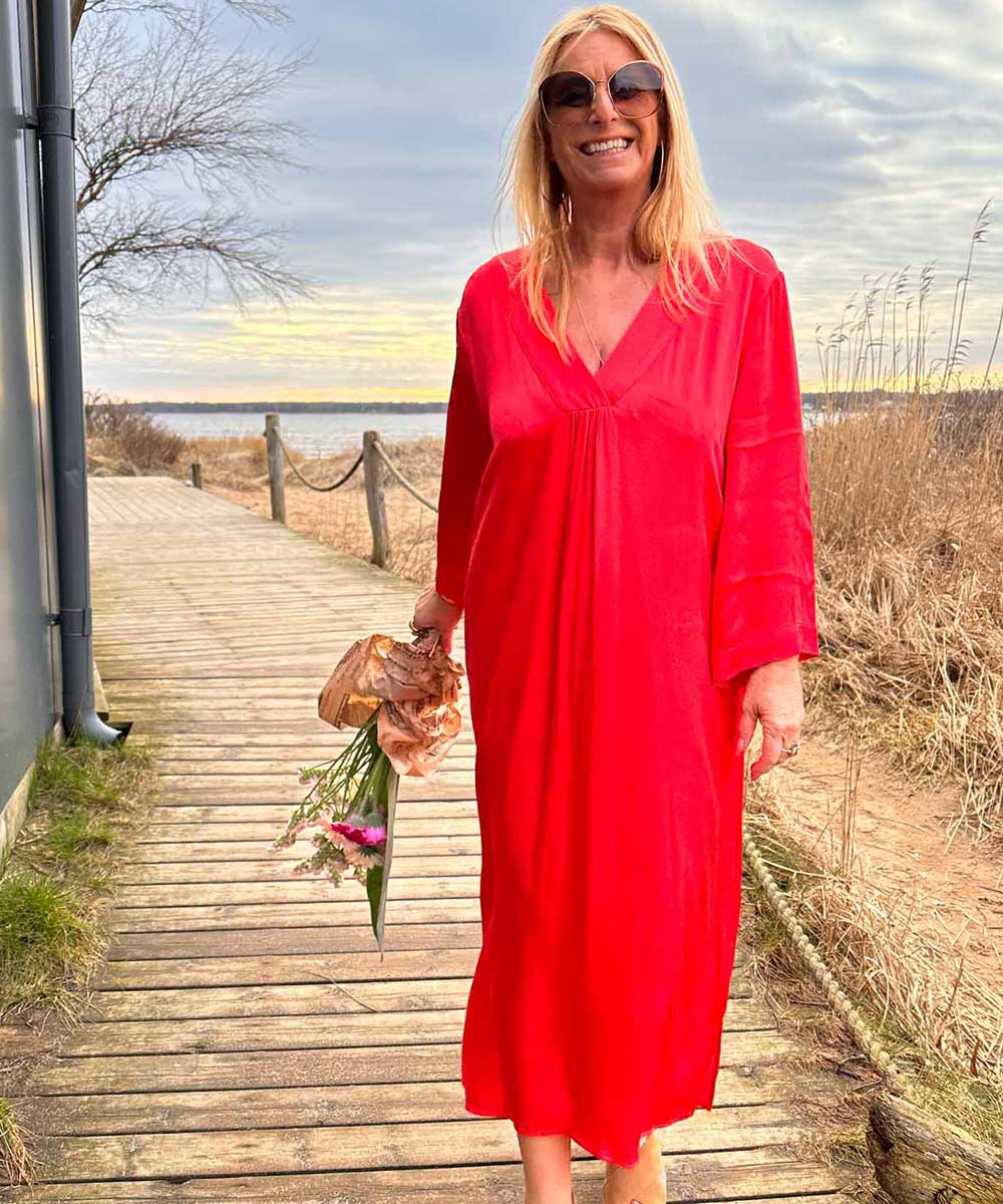 modell på stranden i röd klänning